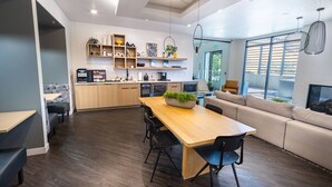Eine moderne Küche mit Holzausstattung, ein Essbereich mit Holztisch und -stühlen sowie eine Sitzecke mit Sofa und Kamin.