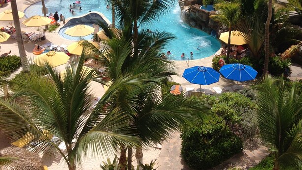 Ein Resort mit mehreren Schwimmbecken, Palmen und Sonnenschirmen.
