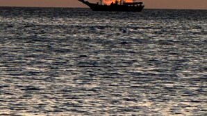 Ein Boot auf ruhigem Wasser, im Hintergrund ein Sonnenuntergang.