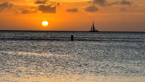 Ein Sonnenuntergang über dem Meer mit einem Segelboot in der Ferne.