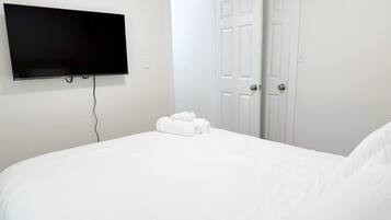 A bedroom with a bed, a flat-screen TV mounted on the wall, and a door.