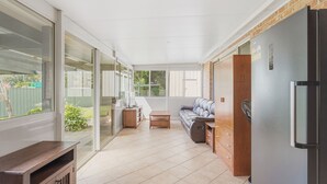 A sunlit room with a sofa, a small table, and a refrigerator. - Boater's Retreat - pet friendly, right off the M1 (Boambee East)