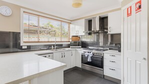 A modern kitchen with white cabinetry, a stainless steel stove, a microwave, and a sink. - Boater's Retreat - pet friendly, right off the M1 (Boambee East)