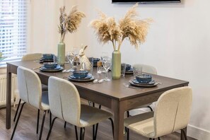 A dining table set with blue plates, glasses, and a vase with dried flowers. - Apartment - Sleeps 7 - Paddington Station 5 Mins (London)