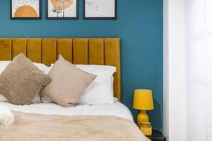 Ein Bett mit zwei Kissen, einer gelben Lampe und einem gerahmten Bild an der Wand.
