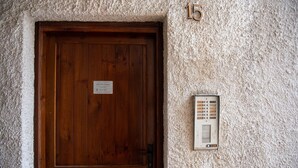 Una porta de fusta amb un cartell i un intercomunicador fixat a la paret.