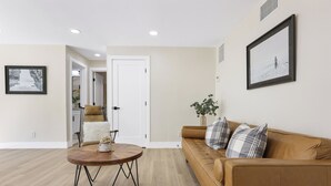A modern living room with a brown leather sofa, a round wooden coffee table, and a framed picture on the wall. - Quiet Newly Renovated Oasis in the Heart of North Park (San Diego)