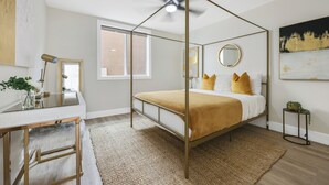 A bedroom with a four-poster bed, a desk with a mirror, a small side table, and a window with a view of the outside. - Quiet Newly Renovated Oasis in the Heart of North Park (San Diego)