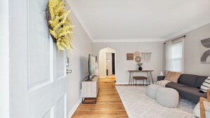 A modern living room with a wooden floor, a grey sofa, and a white rug. - Calming & Relaxing 2br Bungalow near UT, Tol Hosp. (Toledo)