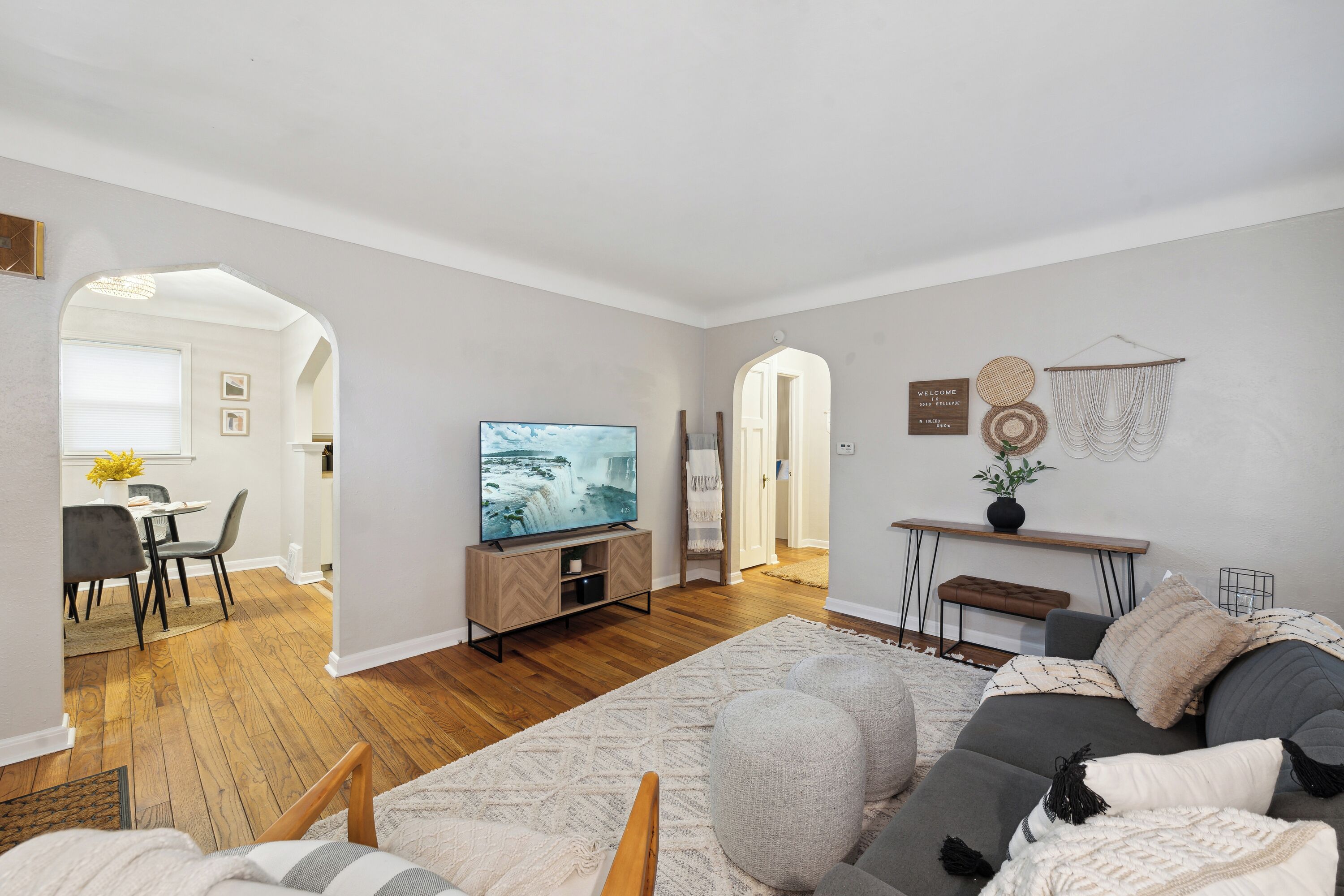 A modern living room with a sofa, TV, and a dining area with chairs and a table.