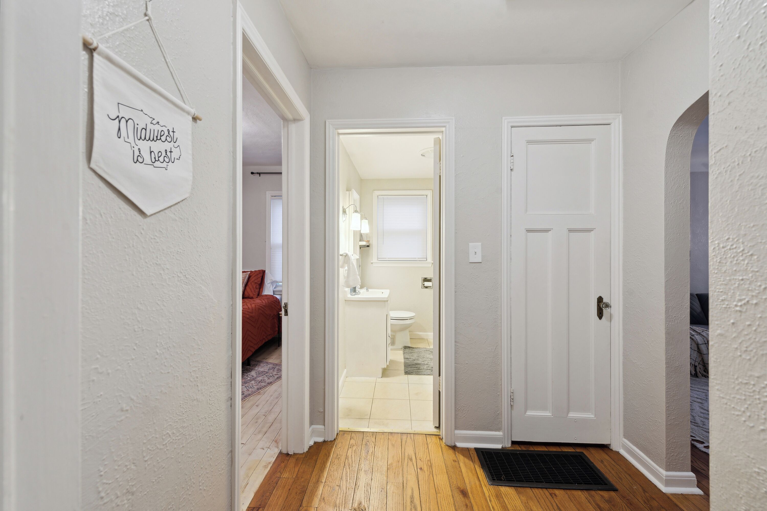 Un couloir avec un plancher en bois, une porte blanche et une pancarte sur laquelle on peut lire : « Le Midwest, c’est le meilleur. »