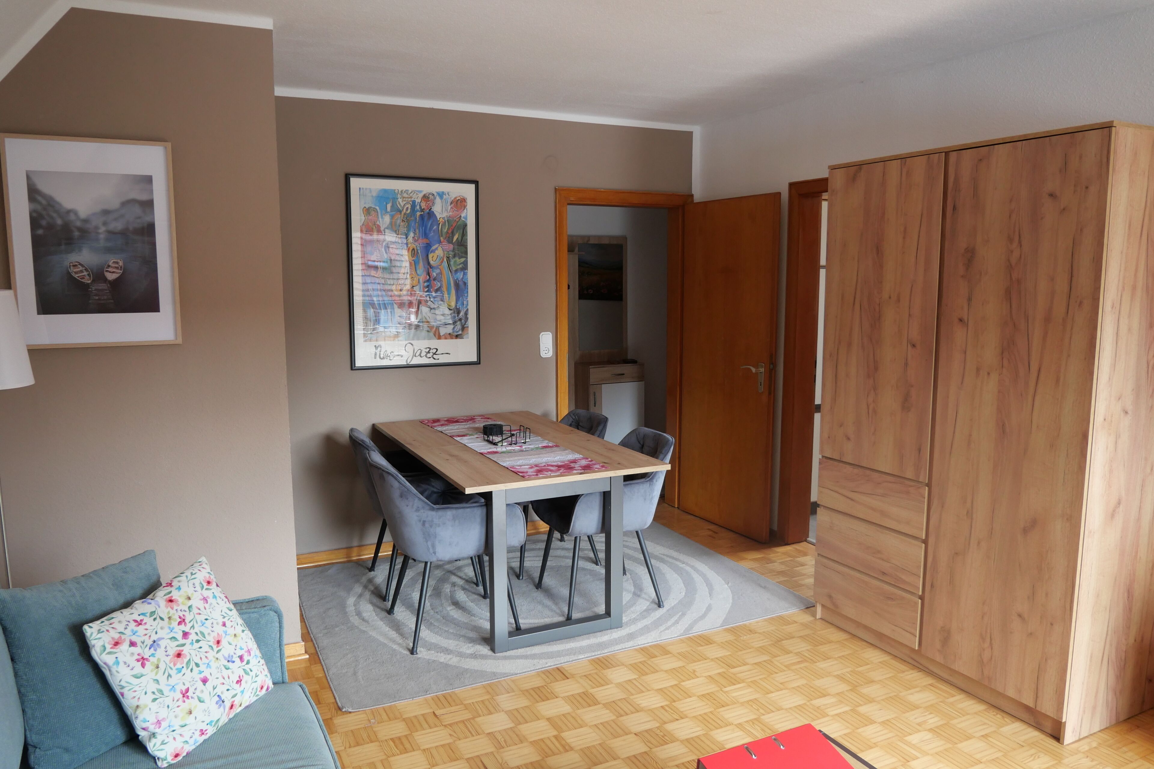 Une pièce comprenant une table à manger, des chaises, un canapé, une grande armoire et un tableau encadré accroché au mur.