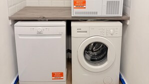 A laundry area with a front-loading washing machine, a top-loading washing machine, and a dryer stacked on top of each other. - Stylish Stay Near Gateacre – South Liverpool (Liverpool)