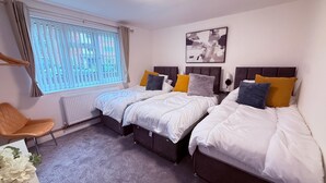 A hotel room with two beds, a radiator, a chair, and a window with blinds. - Stylish Stay Near Gateacre – South Liverpool (Liverpool)