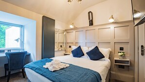 A hotel room with a large bed, a desk, and a chair. There is a window with curtains, a chandelier, and a nightstand with a lamp. - Modern Studio by Howth Marina (Howth)