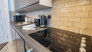 A modern kitchen with a stainless steel sink, a kettle, and a microwave. - Modern Studio by Howth Marina (Howth)