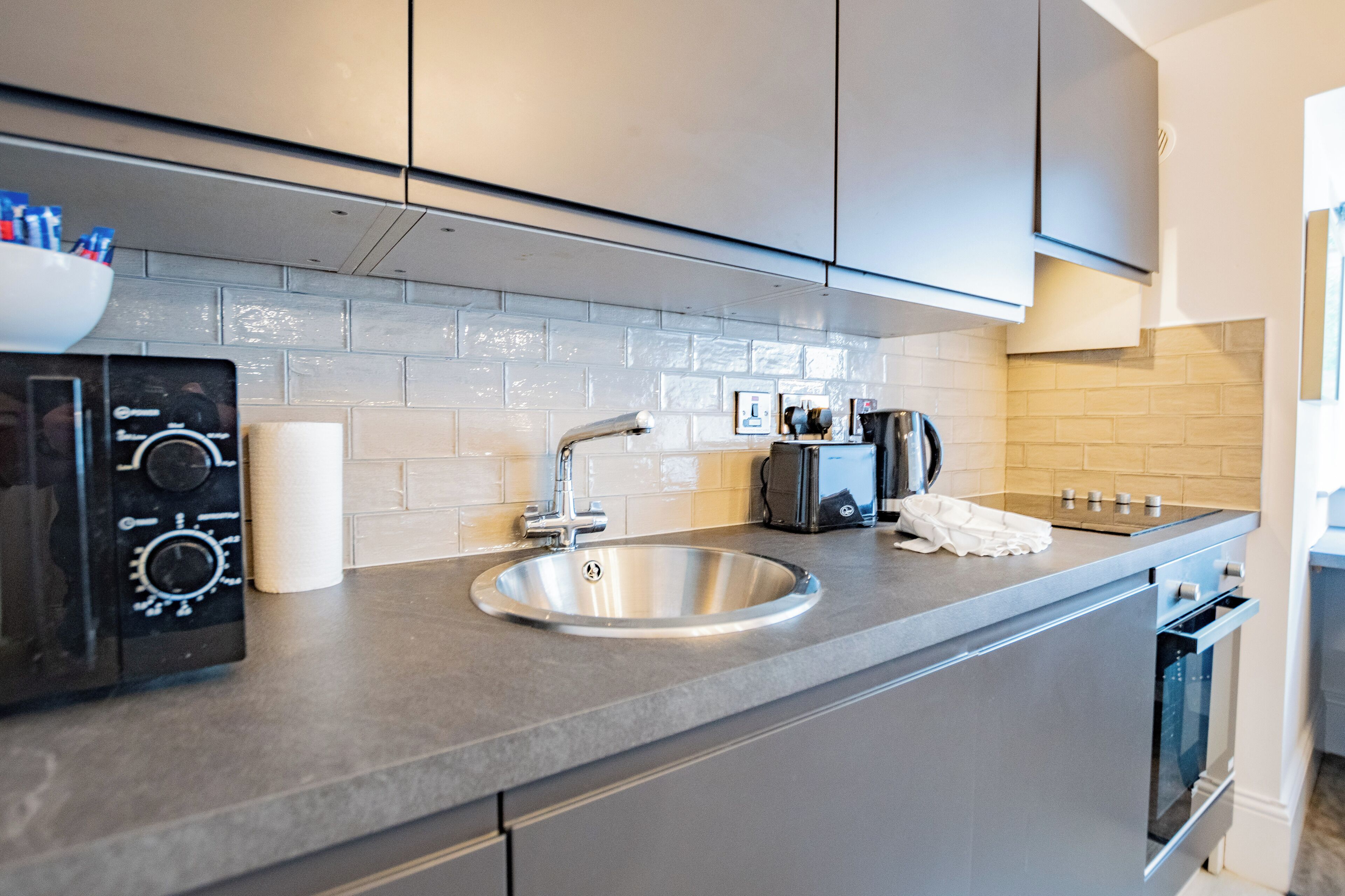 A modern kitchen with a stainless steel sink, a built-in oven, and a microwave.