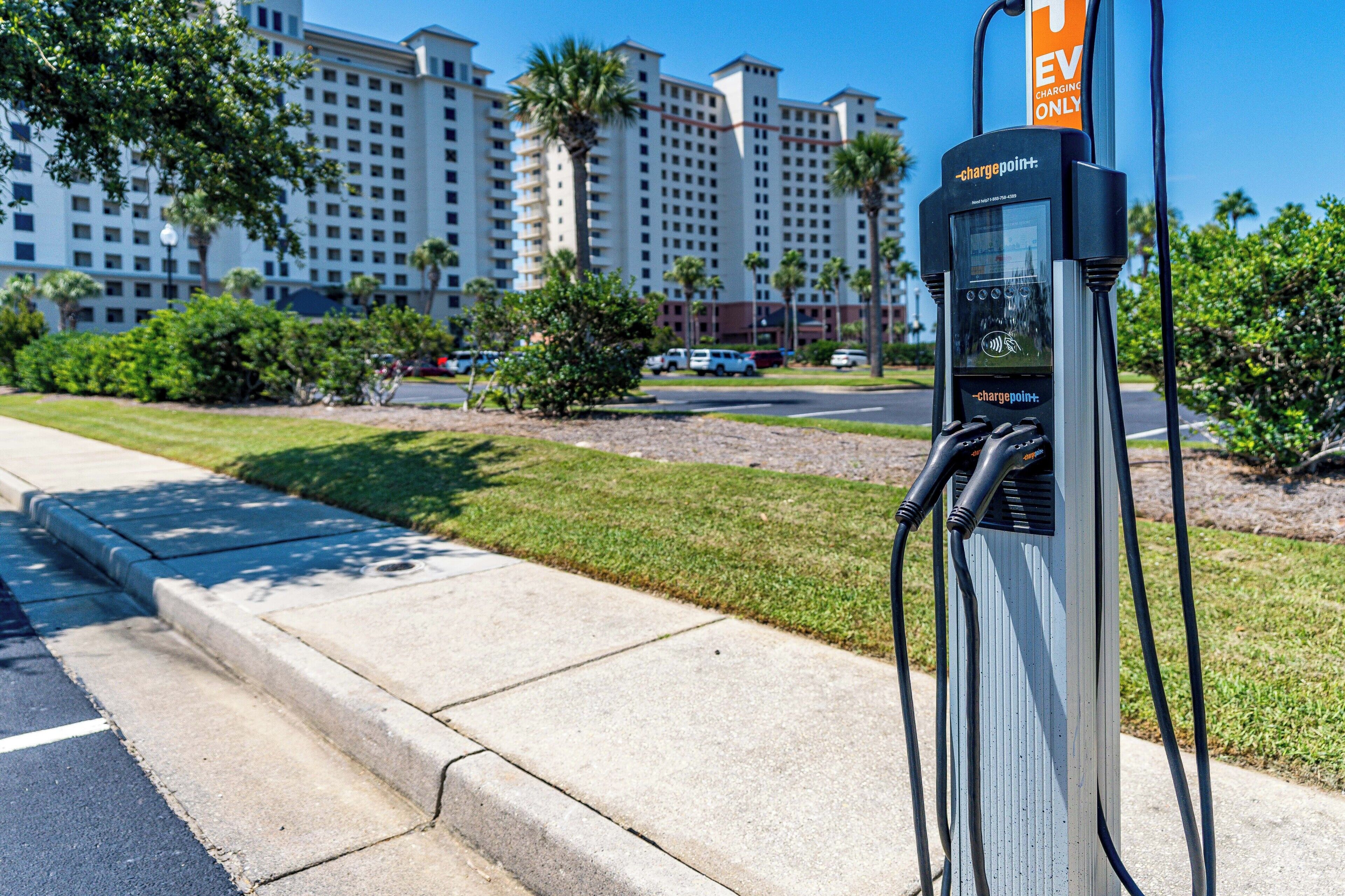 Una estación de carga identificada como 'chargepoint+' con vista despejada a un edificio de hotel de varios pisos.