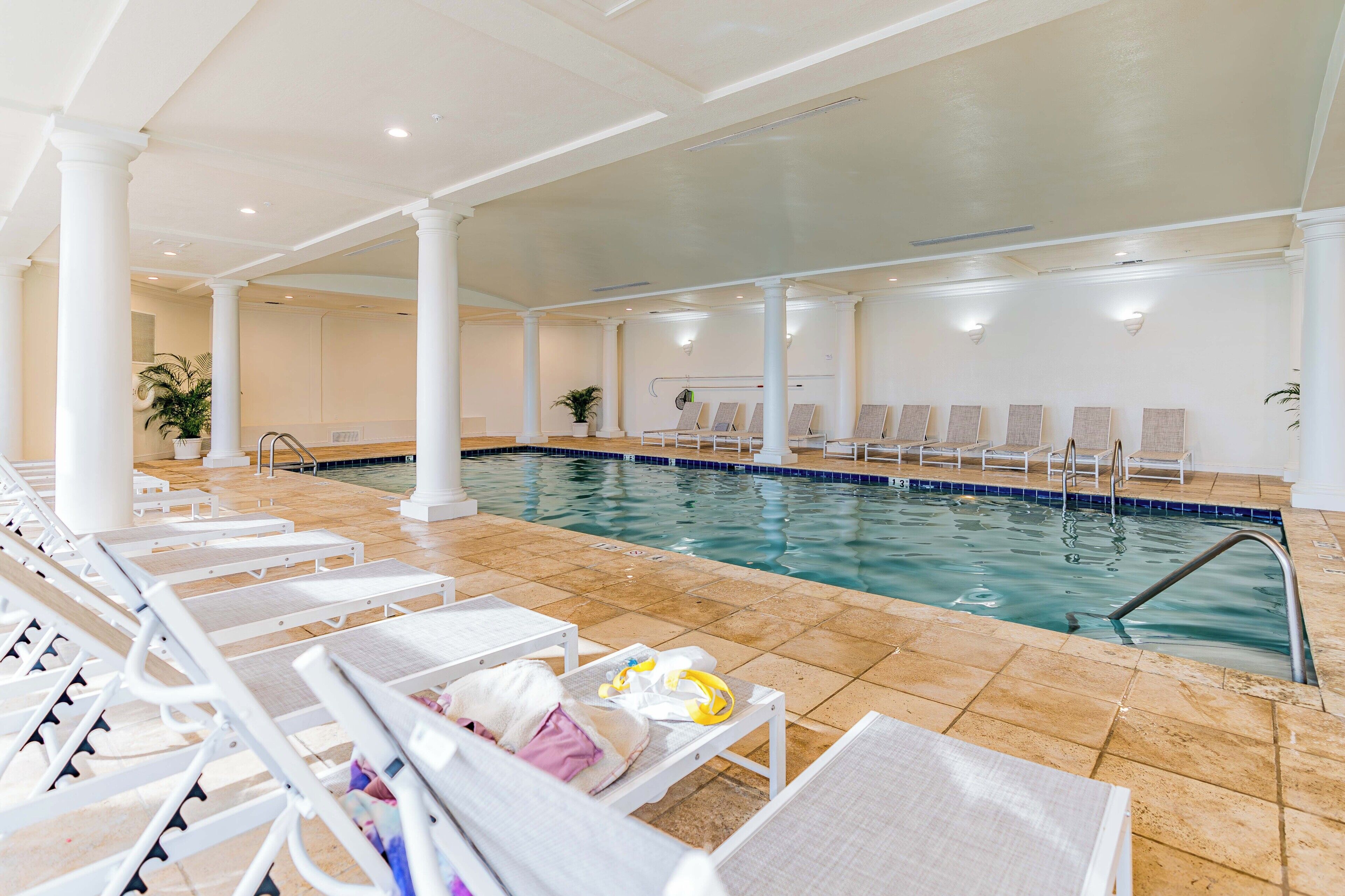 Una piscina interior con sillas de descanso y suelo de baldosas.