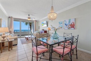 A dining area with a glass table, metal chairs, and a chandelier. - The Beach Club B202 (Gulf Shores)