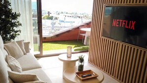 Una sala de estar moderna con un sofá, una mesa de centro y una pantalla de televisión que muestra "NETFLIX".
