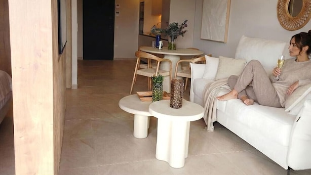 Ein modernes Wohnzimmer mit einem weißen Sofa, zwei runden Beistelltischen und einem Essbereich mit einem kleinen Rundtisch und Stühlen.