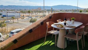 Un comedor con una mesa dispuesta para dos, con vistas a un paisaje urbano y montañas a lo lejos.