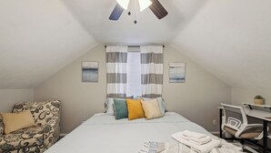 Un dormitorio con cama, una silla, un escritorio y un ventilador de techo.