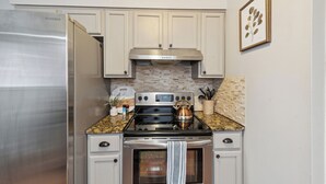 Una cocina con un refrigerador de acero inoxidable, una estufa con un hervidor y un microondas.