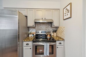 A kitchen with a stainless steel refrigerator, a stove with a kettle, and a microwave. - Spacious & well designed 3br/1.5ba w/ Fiber Wi-Fi! (Toledo)