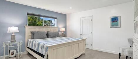 A bedroom with a bed, bedside tables, a chair, and a door.
