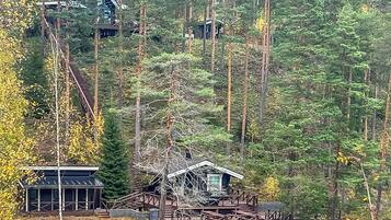 A cabin with a wooden deck and a small boat docked by the water.