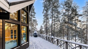 Eine Holzhütte mit großen Fenstern mit Blick auf einen verschneiten Wald.