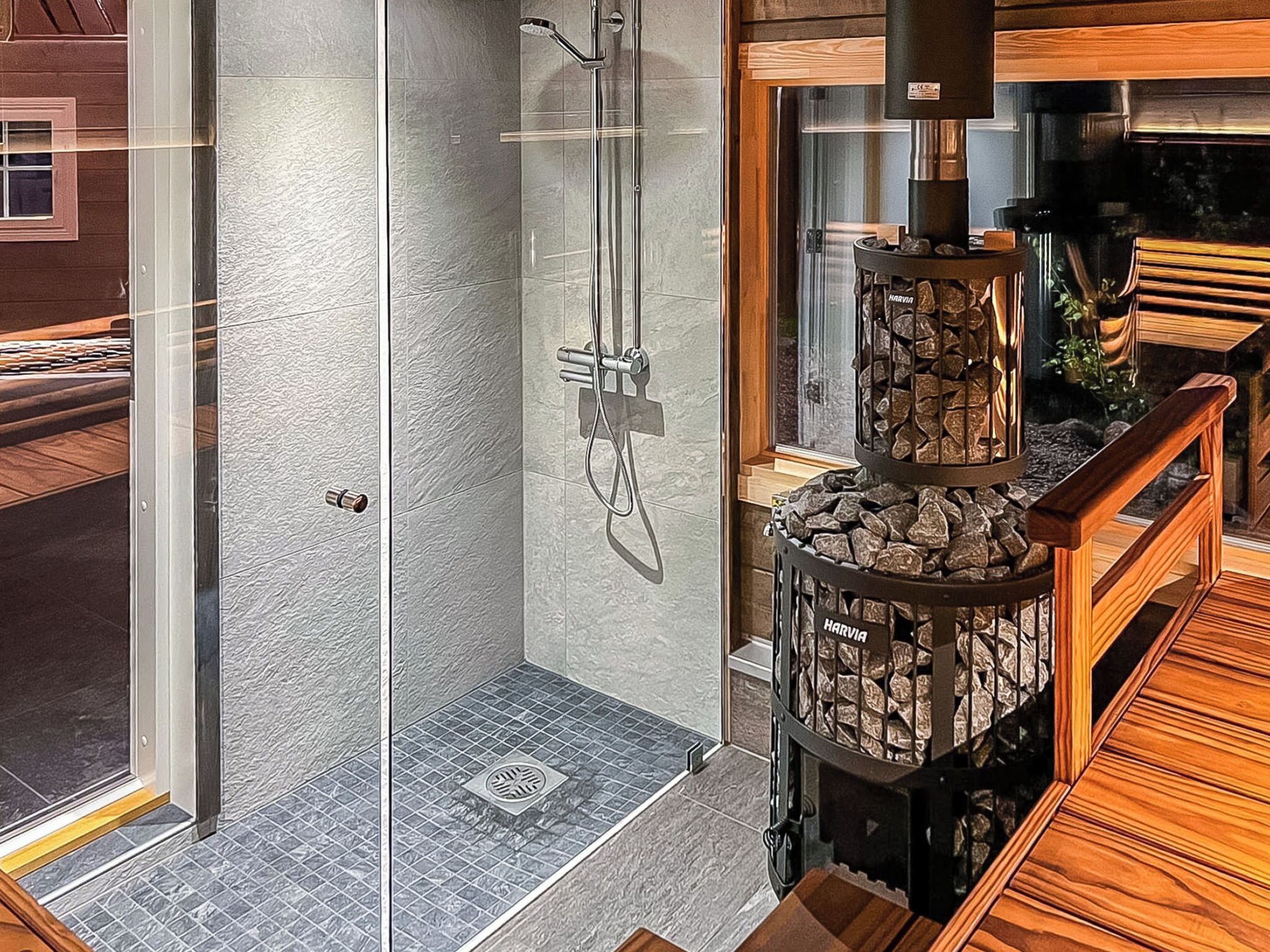 A modern shower enclosure with a glass door, a built-in bench, and a stone fireplace.