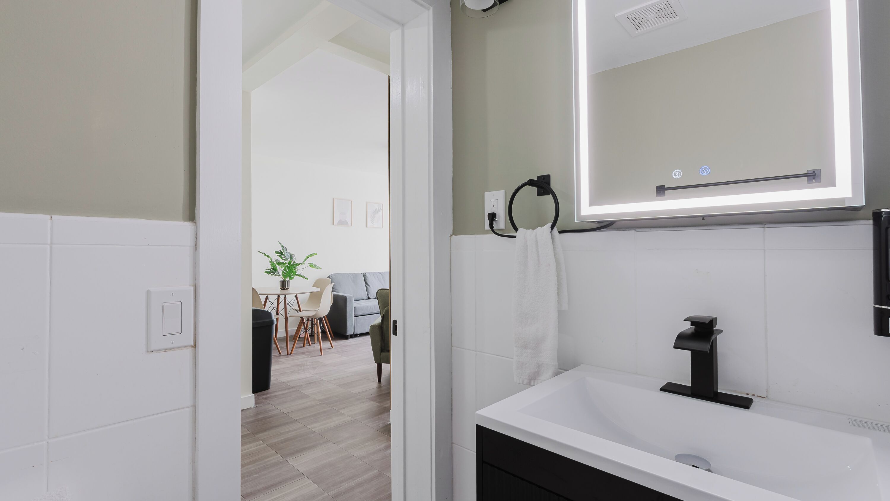 A modern bathroom with a white sink, a mirror, and a towel rack.