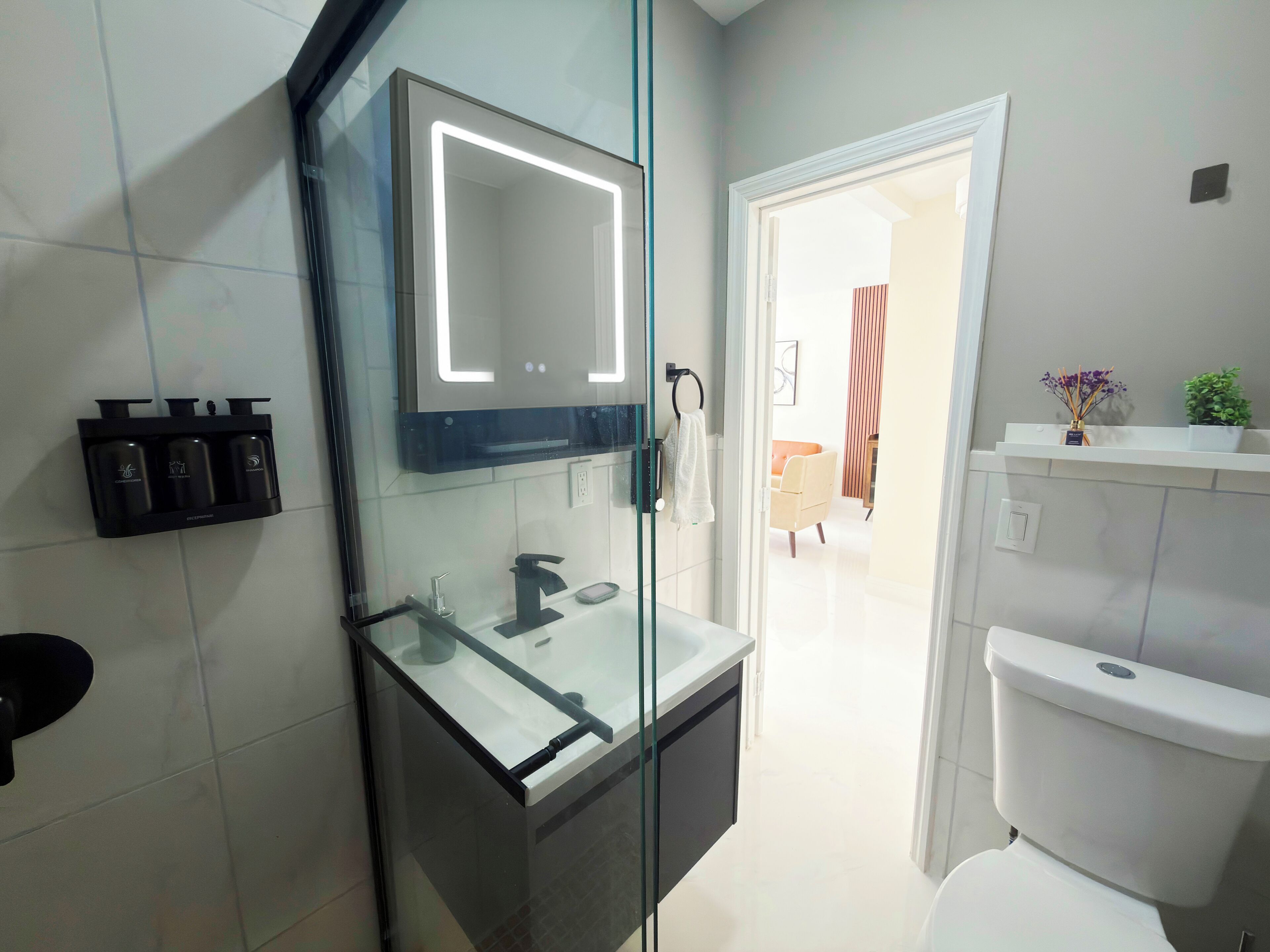 Un baño moderno con ducha de vidrio, inodoro blanco y tocador con espejo.