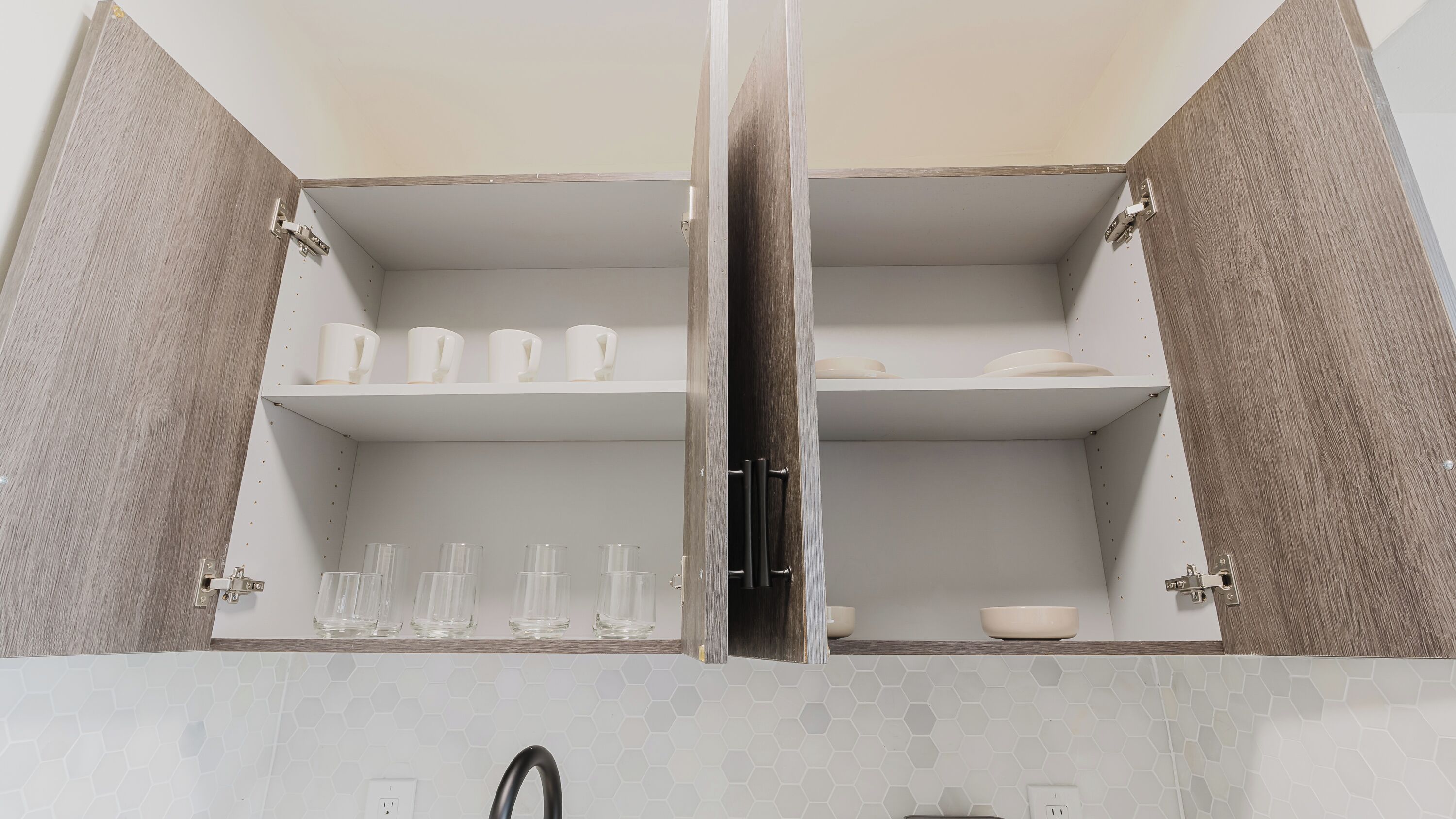 A bathroom with a mirrored cabinet, a sink, and a hexagonal tile backsplash.