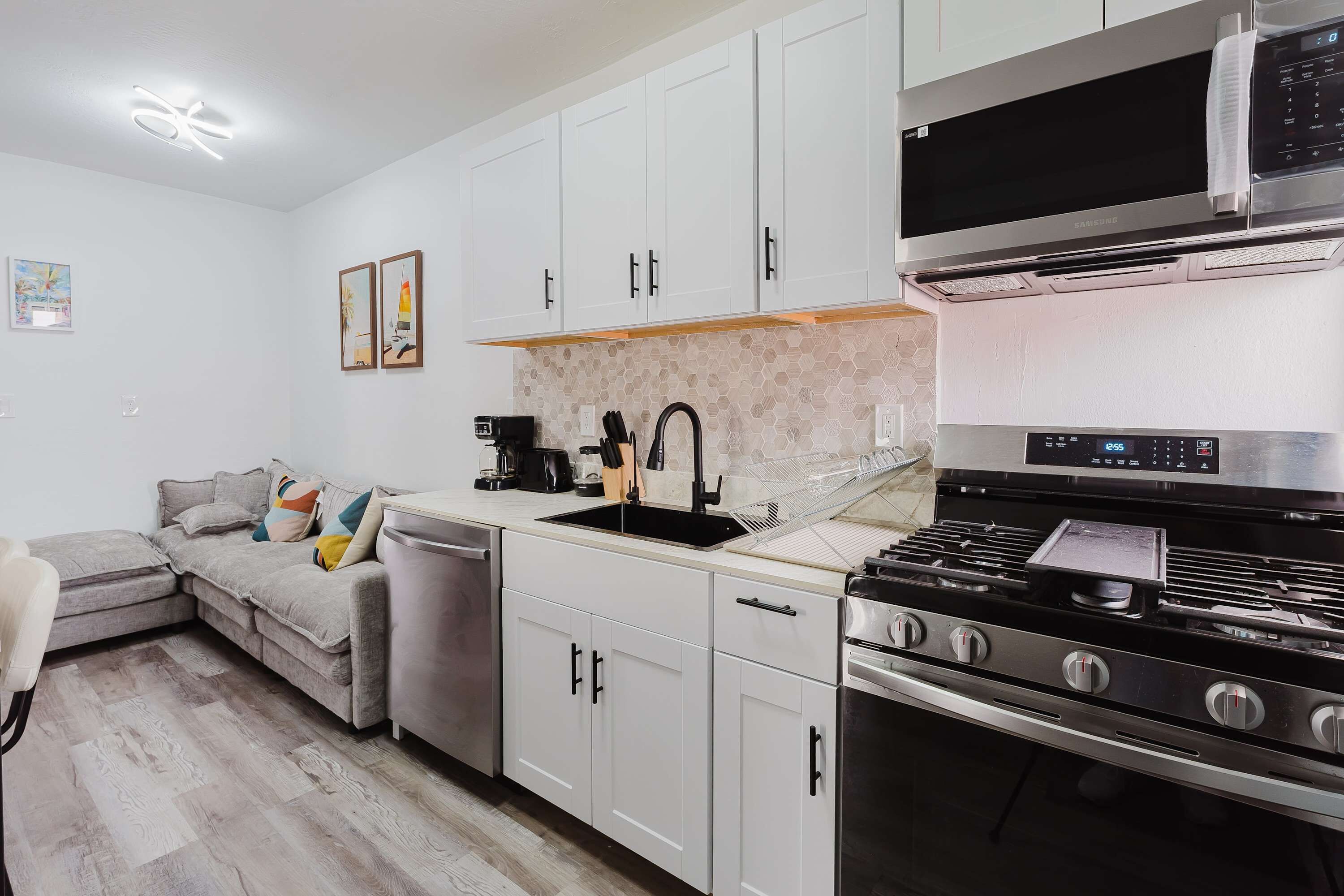 Una cocina moderna con armarios blancos, estufa de acero inoxidable y microondas.