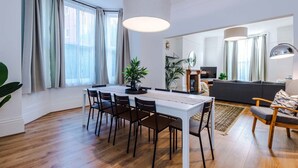 Een moderne woonkamer met een eethoek, grote ramen en een open haard.