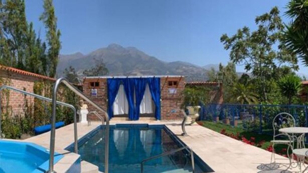 A swimming pool with a hot tub, surrounded by a patio area with stone tiles and a stone wall.