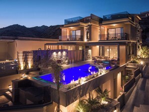 Una casa moderna de varios niveles con piscina, mobiliario exterior y vistas a las montañas.