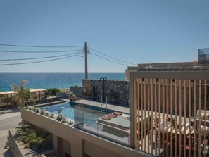 A rooftop pool with a clear view of the sea, surrounded by lounge chairs and a wooden fence. - Lapis Nera Villas (Viannos)