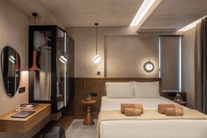 Una habitación de hotel moderna con cama, mesita de noche, lámpara y espejo.
