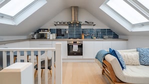 Un appartamento in stile loft con cucina e angolo living, dotato di lucernari, un piano cottura moderno e un'area salotto accogliente.