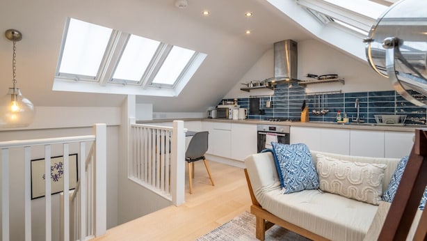Un moderno loft con cucina, zona pranzo e accogliente soggiorno con divano e tavolo da pranzo.