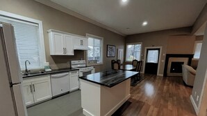 A modern kitchen with white cabinets, a black countertop island, and a wooden floor. - Modern 2BR Walk-Out Suite | 2 Baths | Free Parking (Kelowna)