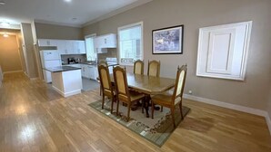 A spacious kitchen with white cabinets, a dining table with six chairs, and a rug on the floor. - Modern 2BR Walk-Out Suite | 2 Baths | Free Parking (Kelowna)
