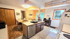 A compact kitchen with a central island, wooden cabinetry, a refrigerator, and a coffee bar. - NEW LISTING 15% OFF 5BR Lake Michigan Cottage Private Retreat • Family Friendly (Pentwater)