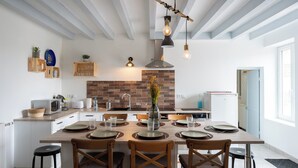 Une cuisine moderne avec un îlot central, des chaises en bois et un mur de fond en briques.