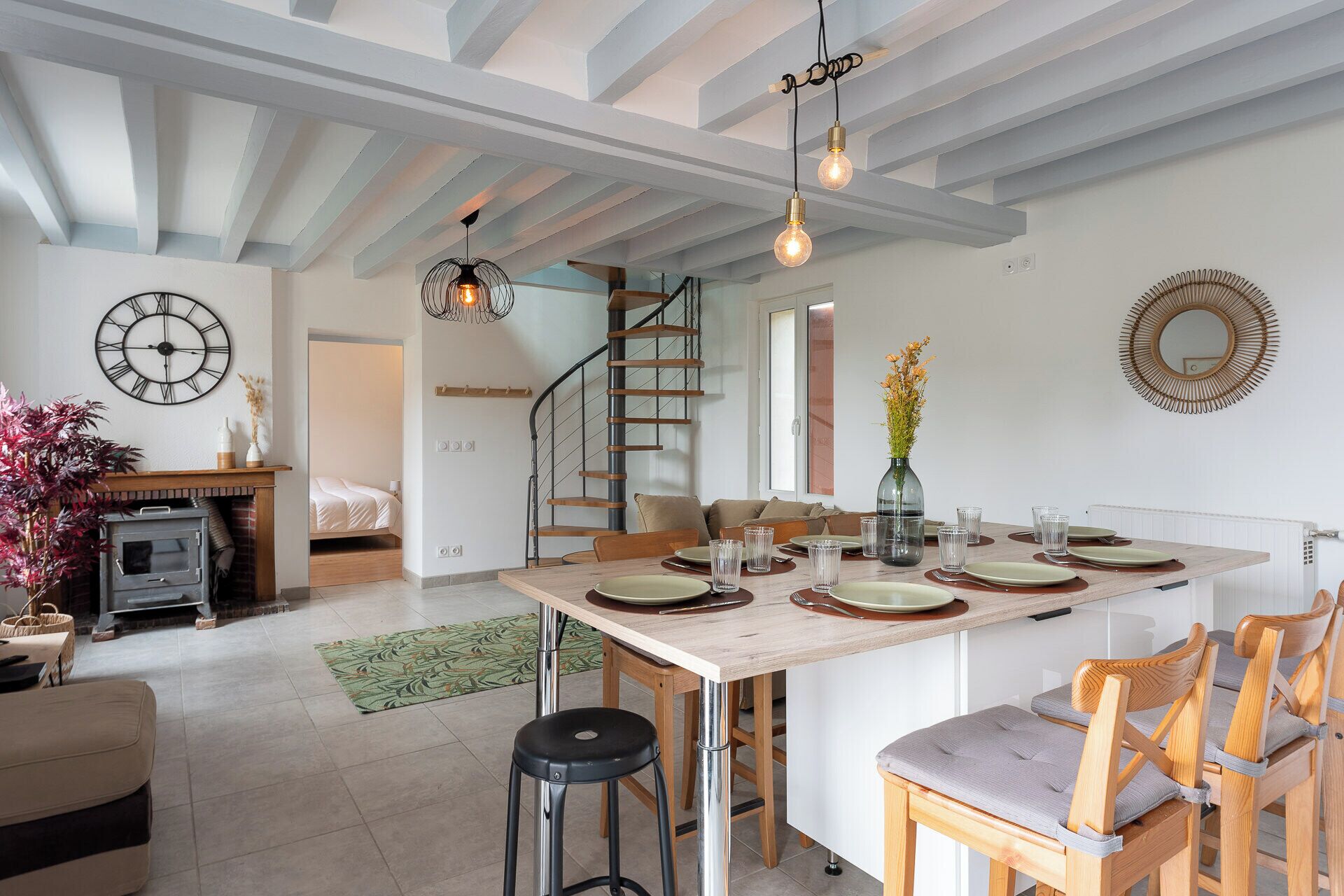 A modern kitchen with a central island, wooden chairs, and a dining table set for four.
